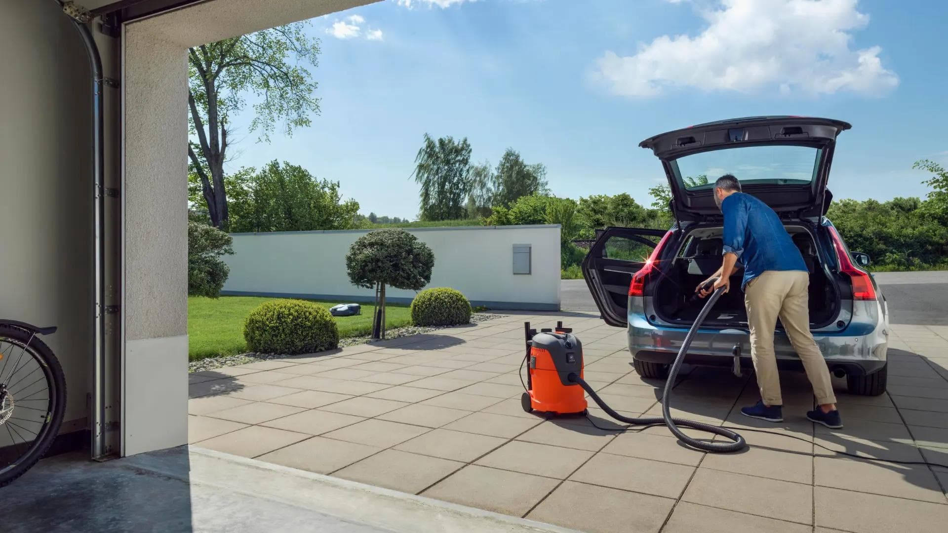 man cleaning boot of car with wet vaccum